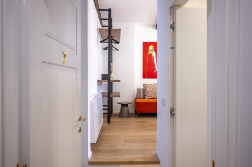 Couloir moderne du Palazzo Garibaldi Parma avec parquet, portes blanches, étagères noires et œuvre d'art rouge en mur