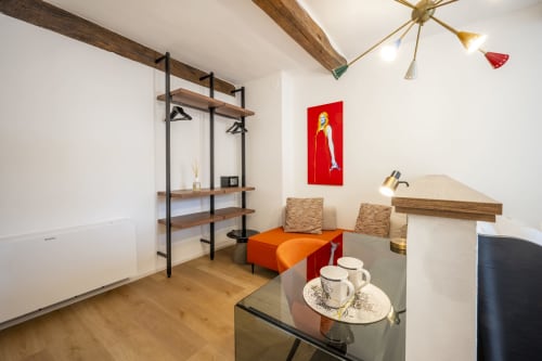 Chambre moderne de l'hôtel Palazzo Garibaldi Parma avec étagères en bois, œuvre d'art rouge et mobilier d'accent orange
