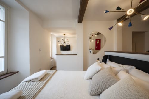 Chambre moderne au Palazzo Garibaldi Parma avec literie blanche, tête de lit noire, miroir rond et luminaires design.