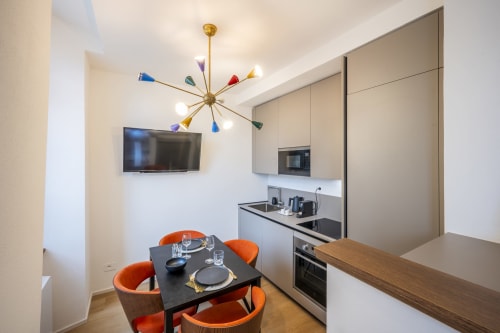 Kitchenette moderne au Palazzo Garibaldi Parma avec table à manger, chaises orange et luminaire suspendu coloré