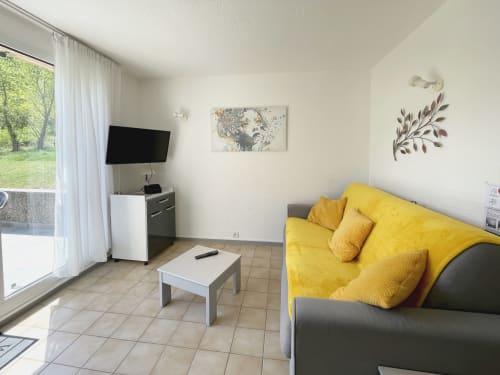 Séjour moderne avec canapé jaune, télévision et vue sur la terrasse à l'hôtel LOCADIGNE à Digne-les-Bains