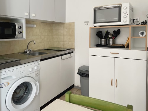 Kitchenette équipée de l'appartement Vallon des Sources avec lave-linge, micro-ondes, évier et appareils de cuisson chez LOCADIGNE