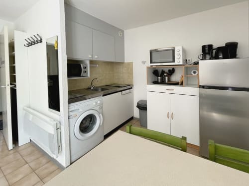 Cuisine moderne et buanderie équipées d'un lave-linge, cuisinière, micro-ondes et rangements à l'appartement Vallon des Sources