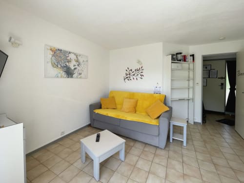 Salon moderne avec canapé gris, coussins jaunes, table basse blanche et œuvres d'art à Locadigne Digne-les-Bains