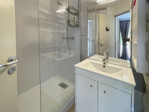 Salle de bain moderne avec douche, vasque blanche et miroir à l'appartement LOCADIGNE à Digne-les-Bains