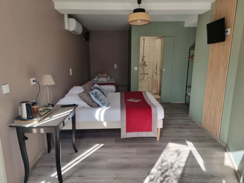 Chambre moderne de l'Hôtel Amadour à Rocamadour avec lit queen-size, bureau, murs verts et entrée de salle de bain
