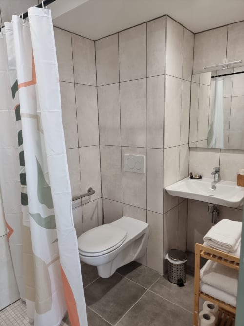 Salle de bain moderne de l'Hôtel Amadour à Rocamadour avec toilettes murales, lavabo et douche