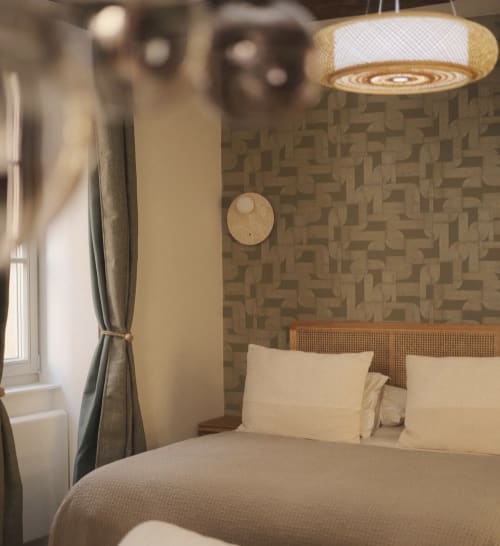 Chambre moderne au Moulin Renaudiots, Autun avec tête de lit en rotin, suspension et papier peint géométrique