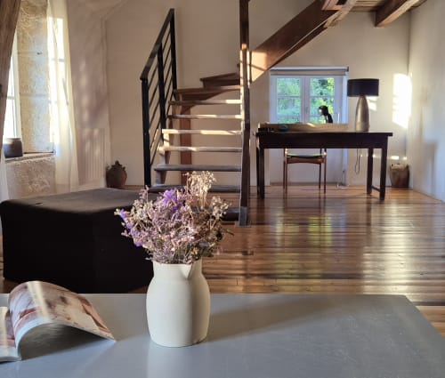 Moulin Renaudiots open-plan living room with wooden stairs, dark desk, and dried flowers in white vase, Autun