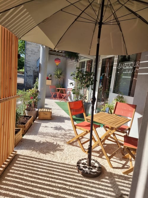 Terrasse de l'Hôtel Amadour avec chaises rouges, parasol et plantes en pot à Rocamadour