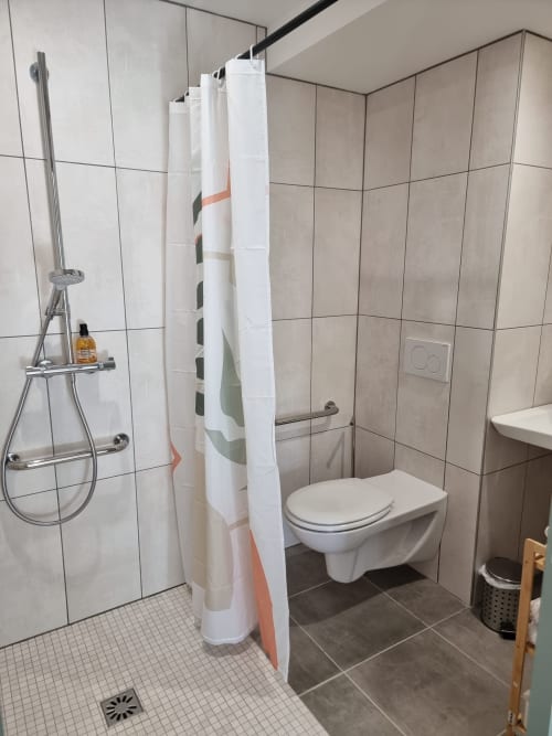 Salle de bain moderne de l'Hôtel Amadour à Rocamadour avec douche à l'italienne, carrelage blanc, toilettes et équipements