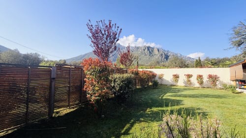 Spacious garden at Villas Vallée d'Asco villa in Corsica with manicured lawn, flowering plants, and mountain views