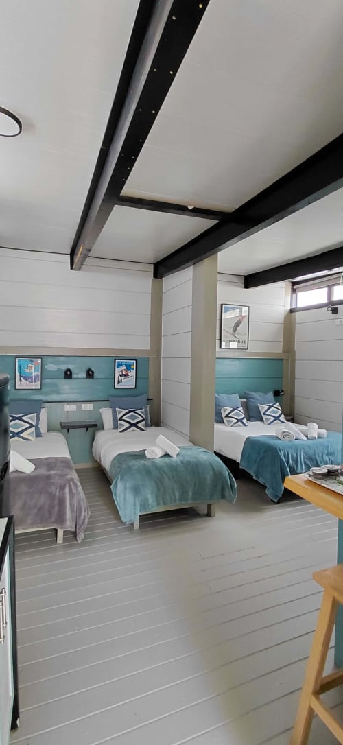 Dormitorio luminoso en Villa Palma, Marbella con camas gemelas, cabeceros turquesas, vigas negras y decoración costera