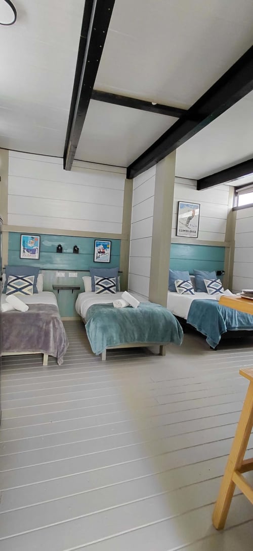 Dormitorio moderno con múltiples camas, cabeceros turquesa y vigas negras en Villa Palma de Marbella