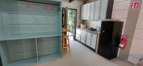 Cocina moderna de Villa Palma Marbella con muebles turquesas, refrigerador negro y comedor con vista al jardín