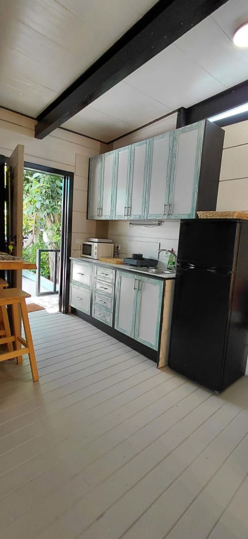 Cocina moderna con armarios turquesas, refrigerador negro y vigas de madera en Villa Palma, Marbella