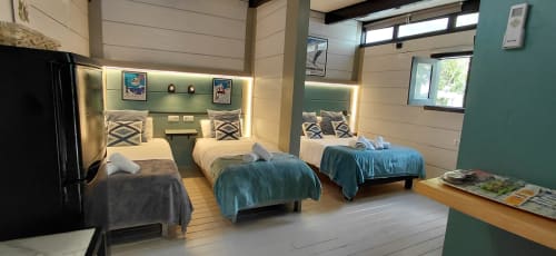 Dormitorio moderno en Villa Palma, Marbella: cuatro camas, detalles en verde azulado, vistas al jardín y decoración contemporánea