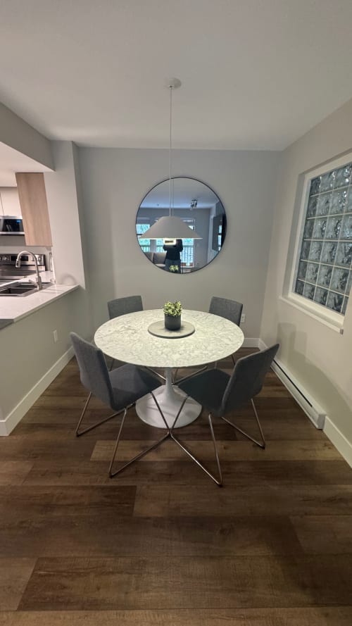 Modern dining area in Northstar 37 Whistler apartment with round marble table, grey chairs, pendant light, and circular