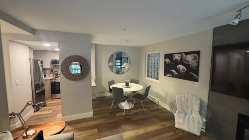Modern apartment living area in Whistler with dining table, flat-screen TV, kitchen access, and contemporary furnishings at