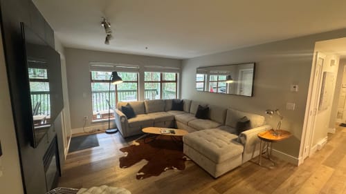 Modern apartment living room in Whistler with L-shaped sectional, wood floors, large windows, and garden views at Northstar