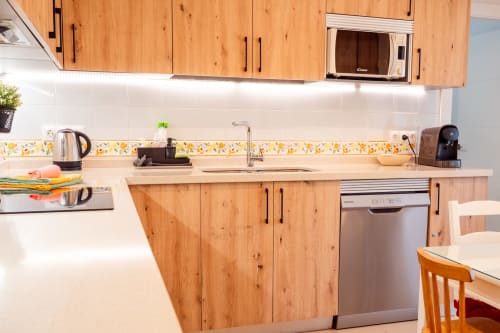 Cocina moderna en Guest Homes Málaga con muebles de madera, encimera blanca y electrodomésticos de acero inoxidable
