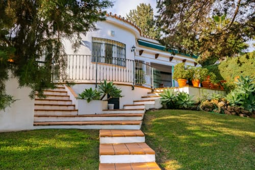 Casas de Huéspedes Málaga - villa española blanca con escaleras de terracota, balcón, jardines exuberantes y árboles maduros