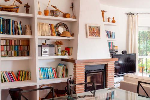 Acogedora sala de estar de casa de huéspedes en Málaga con chimenea, librerías empotradas y mobiliario moderno