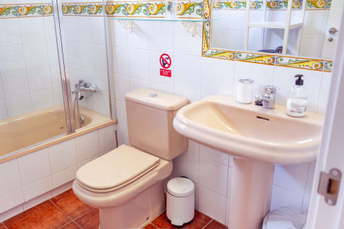 Baño rosa con inodoro, lavabo curvo, espejo y ducha en el hotel Guest Homes Málaga