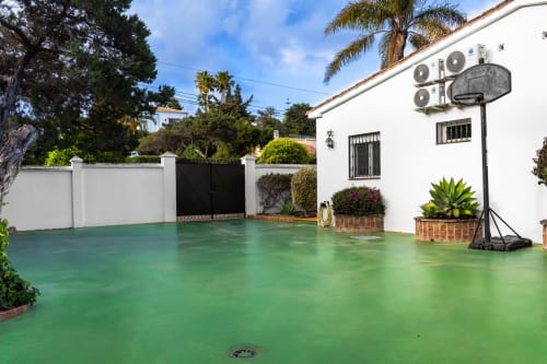 Patio de Guest Homes Málaga con suelo de resina epoxi verde, paredes blancas, palmeras e instalaciones modernas en España
