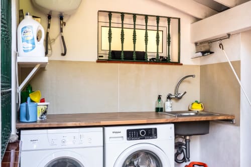 Lavadero compacto en Guest Homes Málaga con lavadora, lavamanos y estanterías de almacenamiento