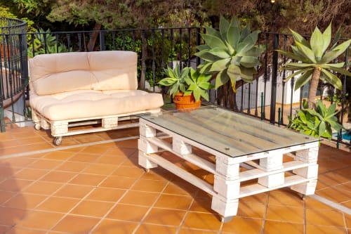 Terraza exterior de Guest Homes Málaga con muebles de palé, asientos acolchados color crema, mesita de café y suculentas en macetas