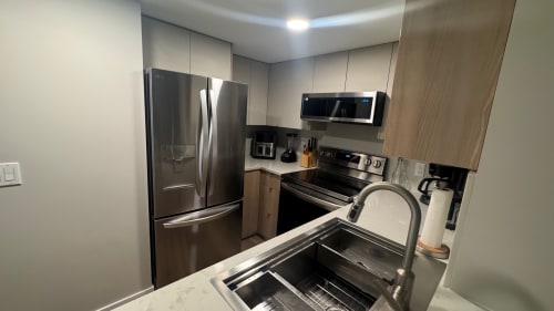 Modern kitchen in Whistler apartment with stainless steel appliances, marble countertop, and sink with faucet