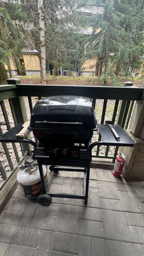 Black gas grill on deck overlooking forest at Northstar 37 apartment in Whistler