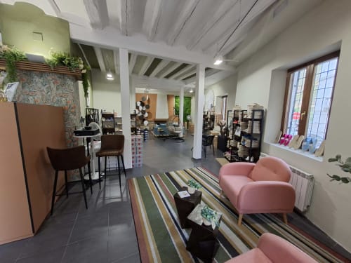 Modern boutique hotel showroom with pink seating, exposed beams, striped rug, and merchandise displays