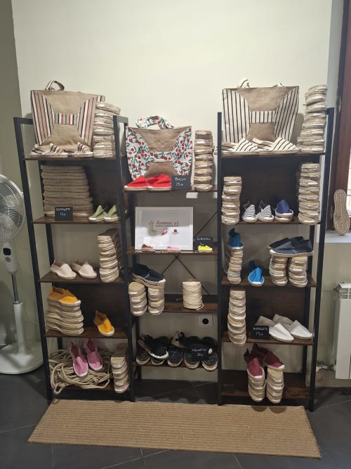 Boutique hotel display shelving with artisanal slippers, textiles, and bags for sale in Cervera del Río Alhama