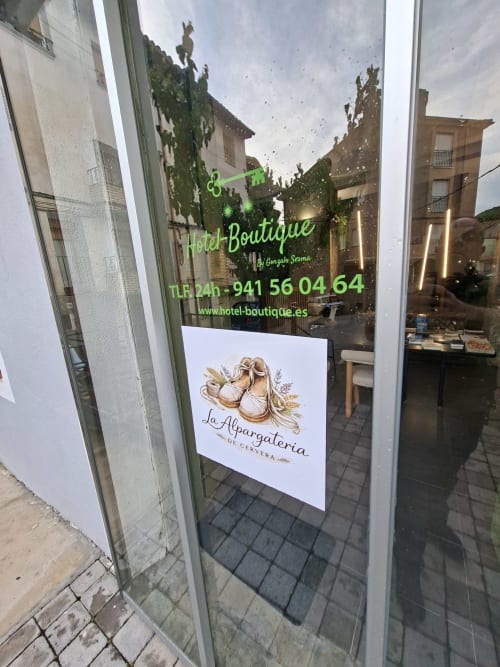 Hotel-Boutique storefront in Cervera del Río Alhama with green neon sign and contact info displayed