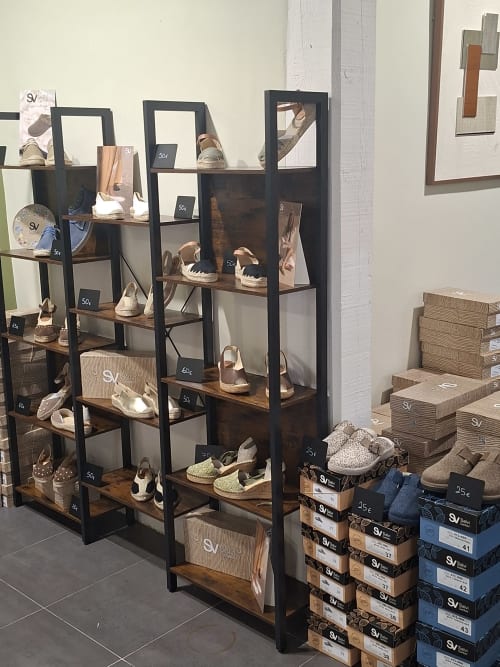 Boutique hotel shoe display with black metal shelving units showcasing esparto sandals and footwear at Hotel-Boutique by