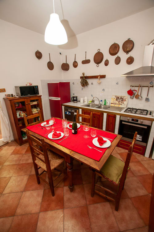 Cristallo Apartment kitchen in Ravenna with wooden dining table, red runner, copper cookware, and pendant lighting