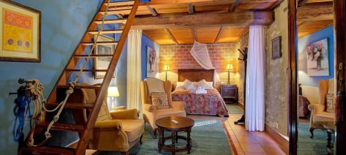 Casa Gallinera luxury suite in Benissivà with wooden beams, brick walls, canopied bed, and wooden staircase