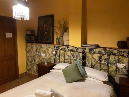 Habitació de Casa Gallinera a Benissivà amb parets grogues, capçal estampat i roba de llit blanca