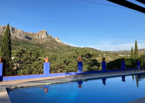Casa Gallinera pool overlooking mountains in Benissivà, Spain with blue walls and cypress trees