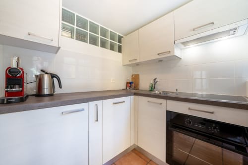 Cuisine moderne de l'Appartement Supérieur Residenza Motta avec armoires blanches, plan de travail foncé et appareils en acier inoxydable