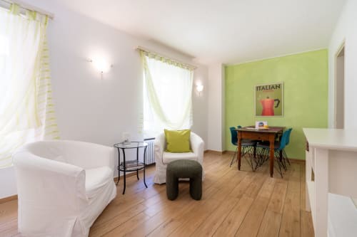 Appartement lumineux 2 pièces à la Residenza Motta Locarno avec mur accent vert citron, mobilier blanc, parquet et jardin