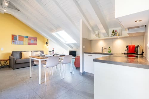 Penthouse moderne à la Residenza Motta Locarno avec cuisine ouverte, salle à manger et séjour aux murs jaunes