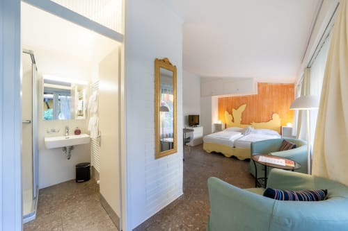Monolocale presso la Residenza Motta a Locarno con letti gemelli, testata arancione, zona living e bagno en suite