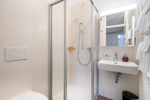 Salle de bains moderne avec cabine de douche, lavabo blanc et miroir à la Residenza Motta B&B à Locarno