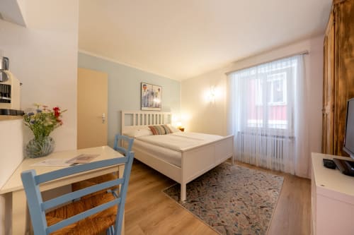 Monolocale luminoso alla Residenza Motta a Locarno con letto, scrivania, pavimenti in legno e vista sulla città