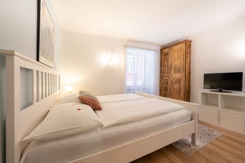 Studio moderne à la Residenza Motta Locarno avec lit blanc, armoire en bois, TV et vue sur la ville