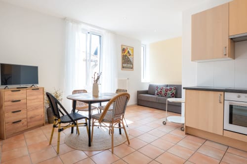 Lumineux appartement ouvert à Residenza Motta, Locarno. Coin repas avec cuisine, salon avec canapé, mobilier en bois