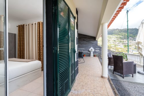 Modern apartment hallway with open terrace, black doors, sea view balcony overlooking Arco da Calheta, Portugal, showing